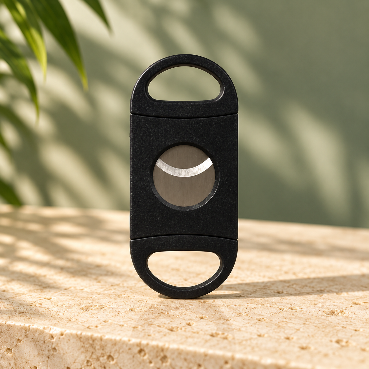 MSWK Miswak Cutter: black double-blade pocket cutter with two D-shaped finger handles, standing upright on travertine